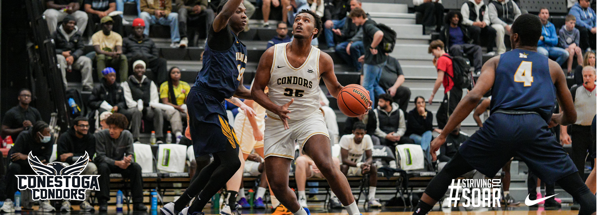 A photo banner with Emanuel Liyaw driving to the net in a basketball game while being defended by a humber student athlete. 