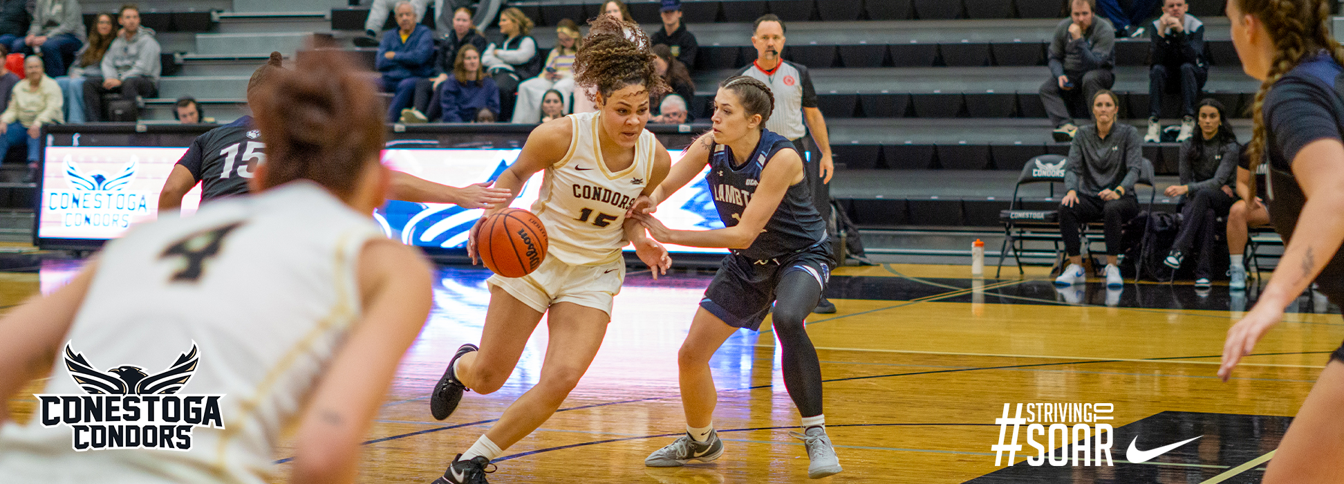 A photo banner of Jamila Beckford driving past a defender in a basketball game. 